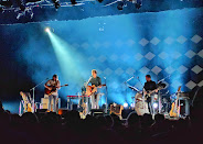 Guitarists performing under blue stage lights at Théâtre Le Patriote