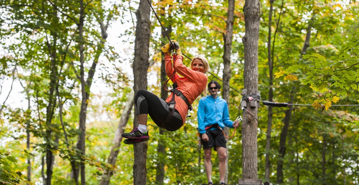 Girl in orange/red jacket on forest zipline